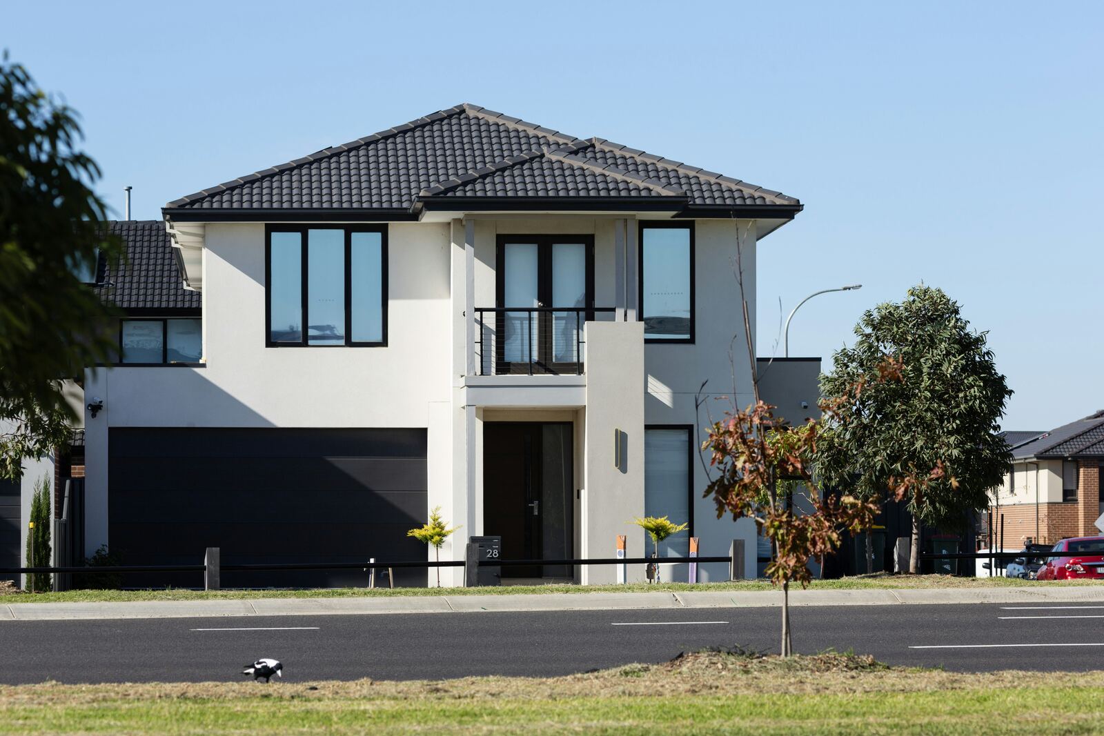 Exterior of a modern two-story renovation with dark garage door and large windows
